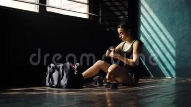 惊慌失措的年轻美女坐在地板上，用黑色拳击包裹在俱乐部里的手。